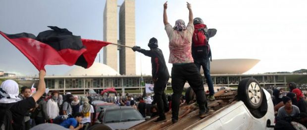 Anti-government demonstrators gesture atop a press car of Tv Record as they attend a demonstration against a constitutional amendment, known as PEC 55, that limits public spending, in front of Brazil's National Congress in Brasilia