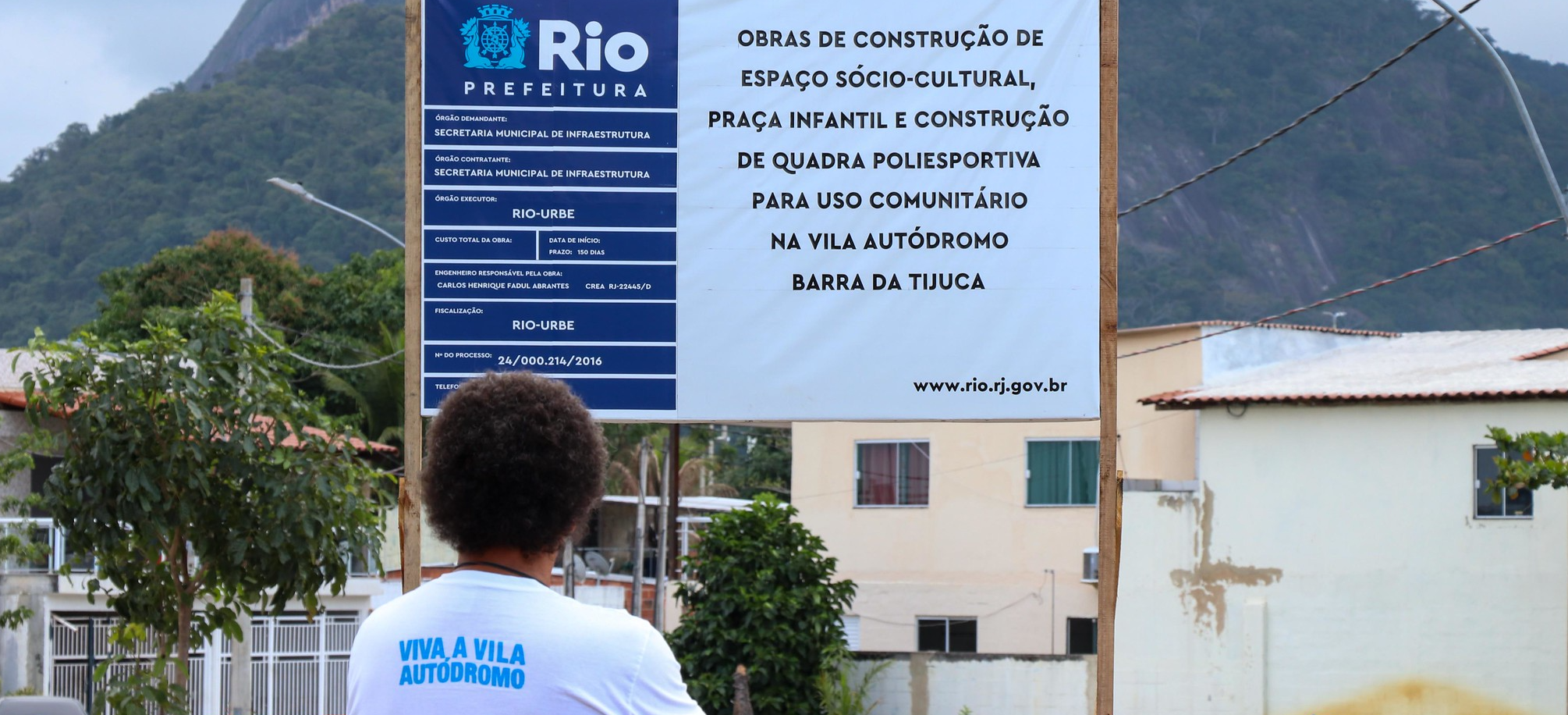 Luiz Cláudio Silva, morador e representante do Museu das Remoções, observa a placa de identificação das obras na entrada da comunidade. Foto: Alexandre Cerqueira