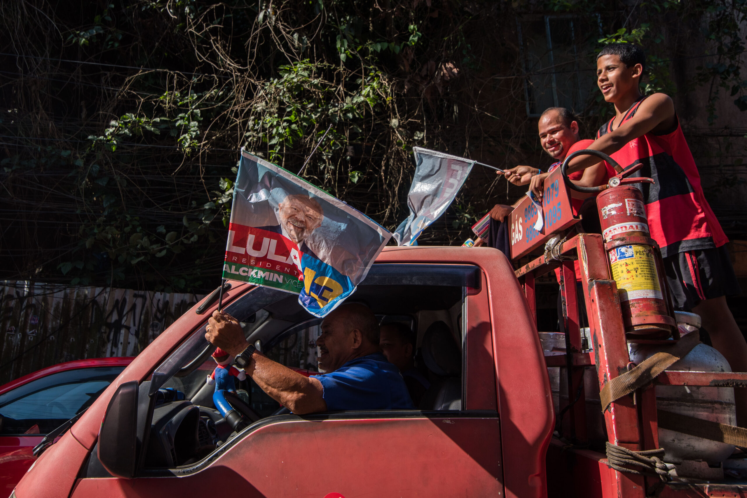 Moradores da Rocinha demonstram apoio à Caminhada Rocinha com Lula acenando da janela e da traseira de carros. Foto: Bárbara Dias/RioOnWatch