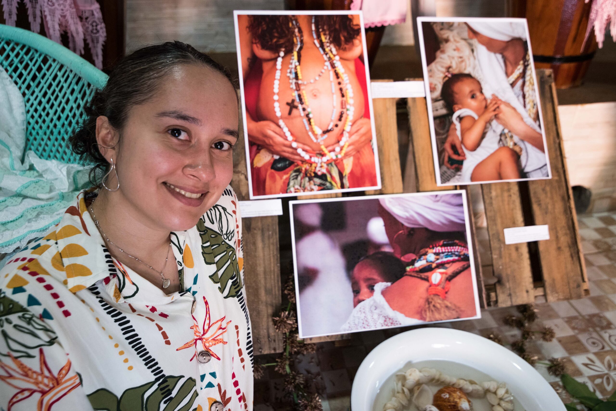 A fotógrafa Clara Nascimento posa em frente a suas fotos preferidas da exposição Pedrinhas Miudinhas. Foto: Bárbara Dias