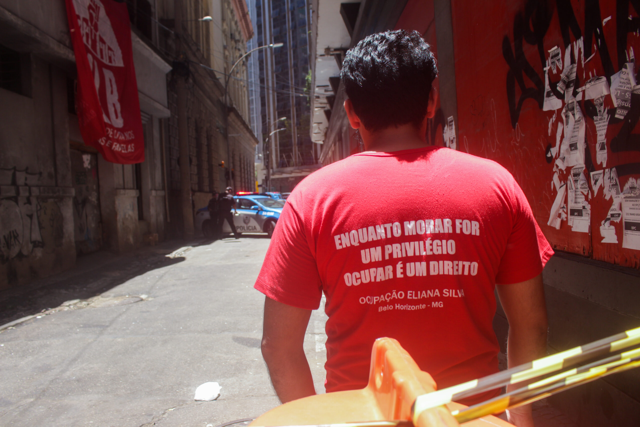 Militante do MLB veste camisa escrita 'Enquanto morar for um privilégio, ocupar é um direito' em frente à Ocupação Luiz Gama. Foto: Vinícius Ribeiro
