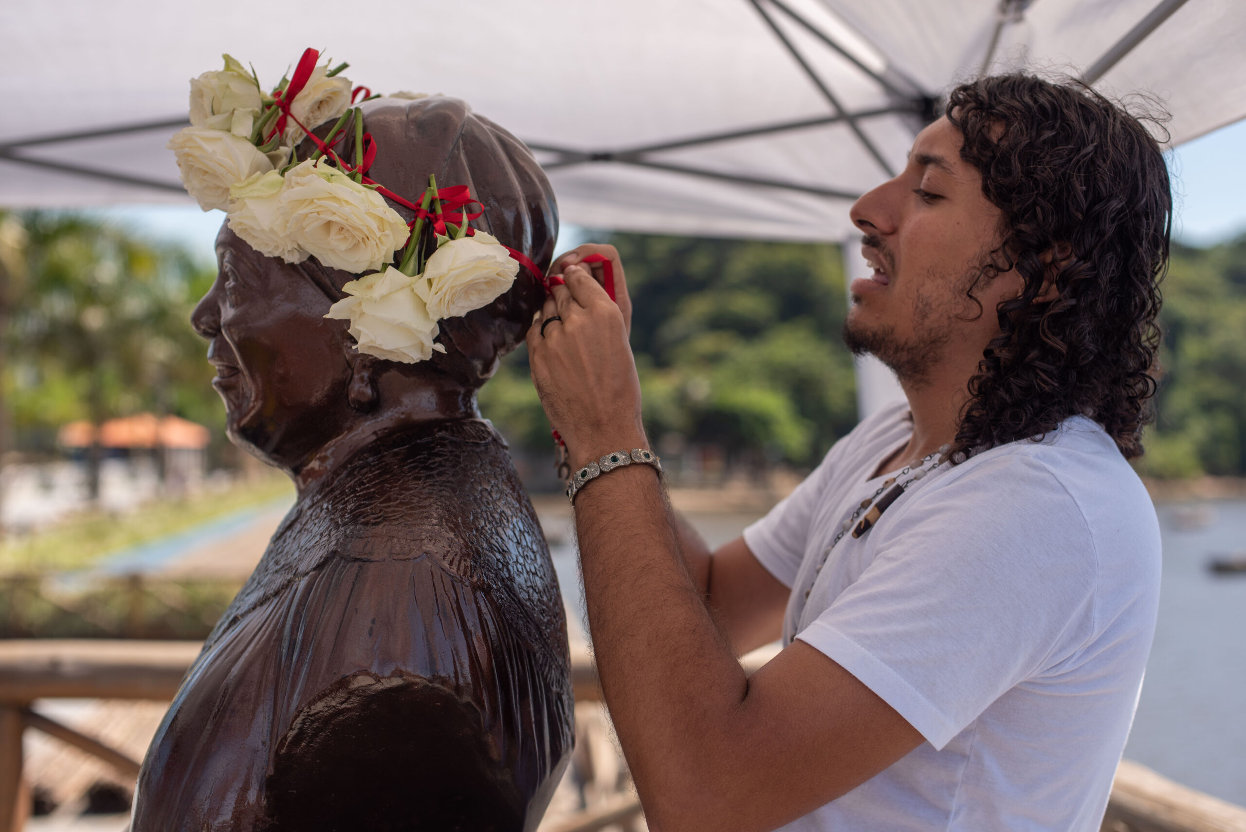 Marcos Cesar, um dos organizadores do ato, coroando o busto de Maria Conga, numa tentativa de reparação ao ato de vandalismo que o monumento havia sofrido há poucos dias. Foto: Bárbara Dias