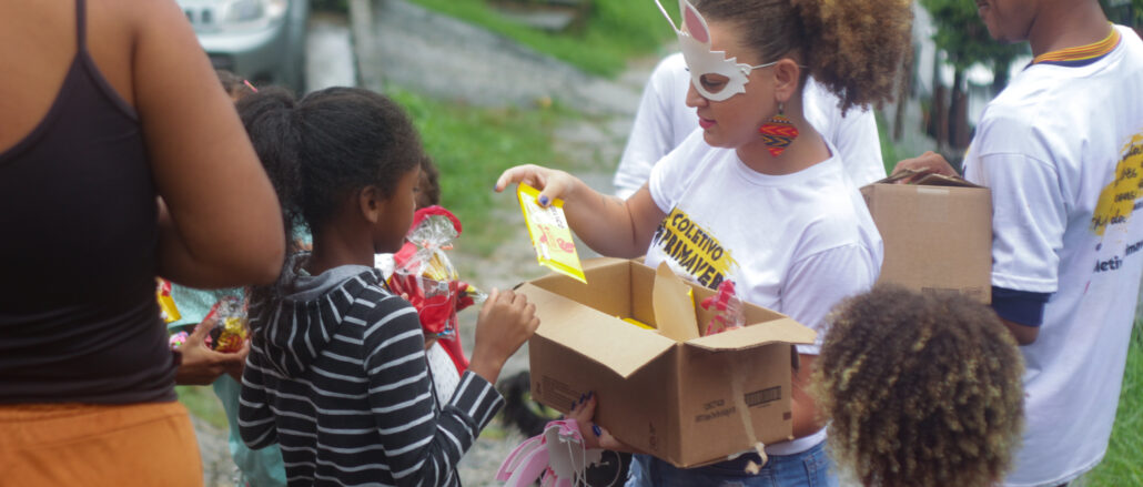 Integrantes do Coletivo Primavera distribuindo kits de chocolate na ação de Páscoa, em Cavalcanti. Foto: Vinícius Ribeiro