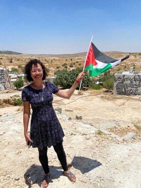 Gizele Martins, comunicadora popular da Maré, em um vilarejo beduíno na Palestina, segura a bandeira da Palestina. Foto: Arquivo Pessoal