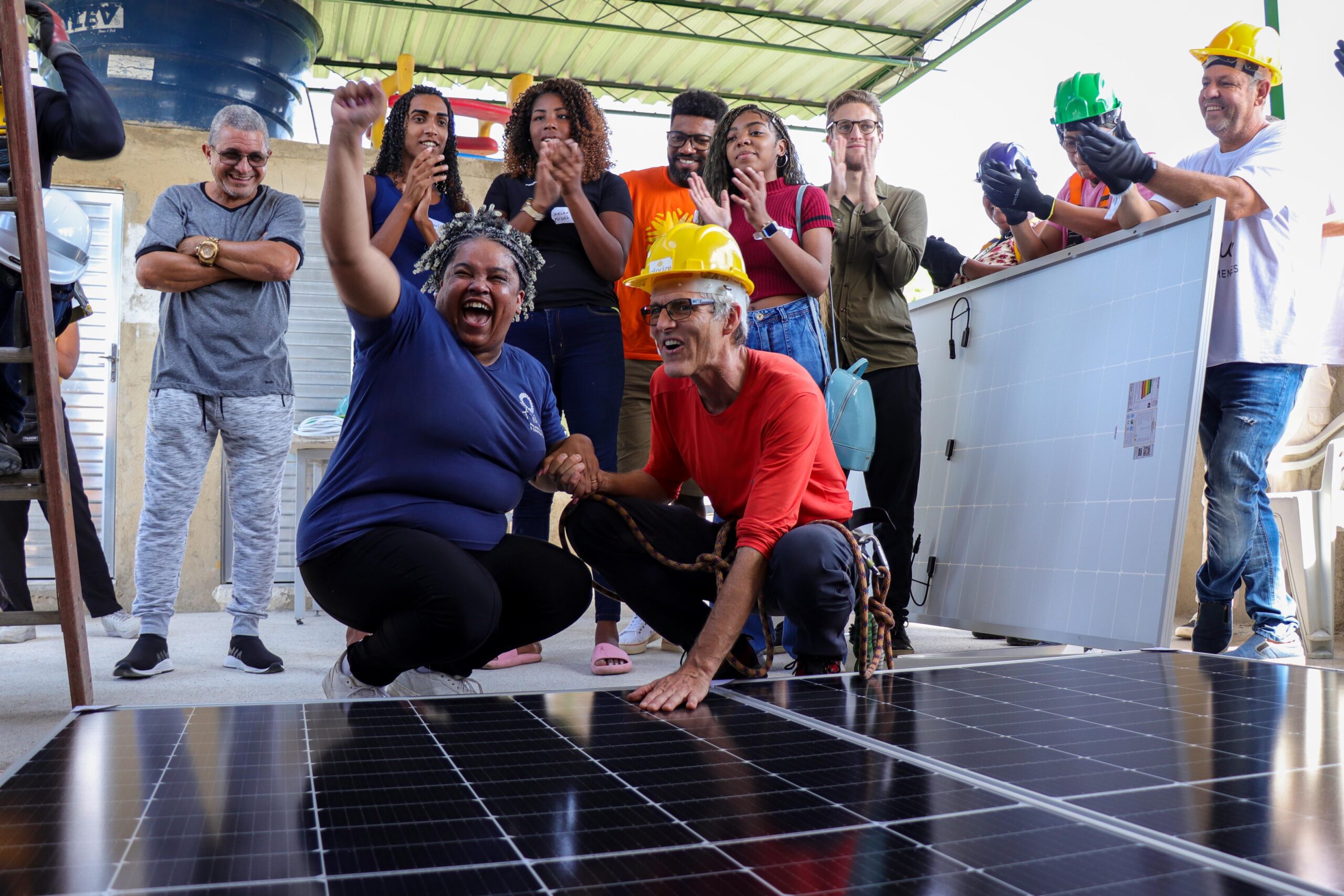 Nill Santos, presidente da AMAC, comemora o recebimento das placas fotovoltaicas na sede da associação junto de Hans Rauschmayer, da Solarize. Foto: Alexandre Cerqueira